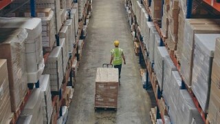 Male pulling a trolley full of shipments in a warehouse